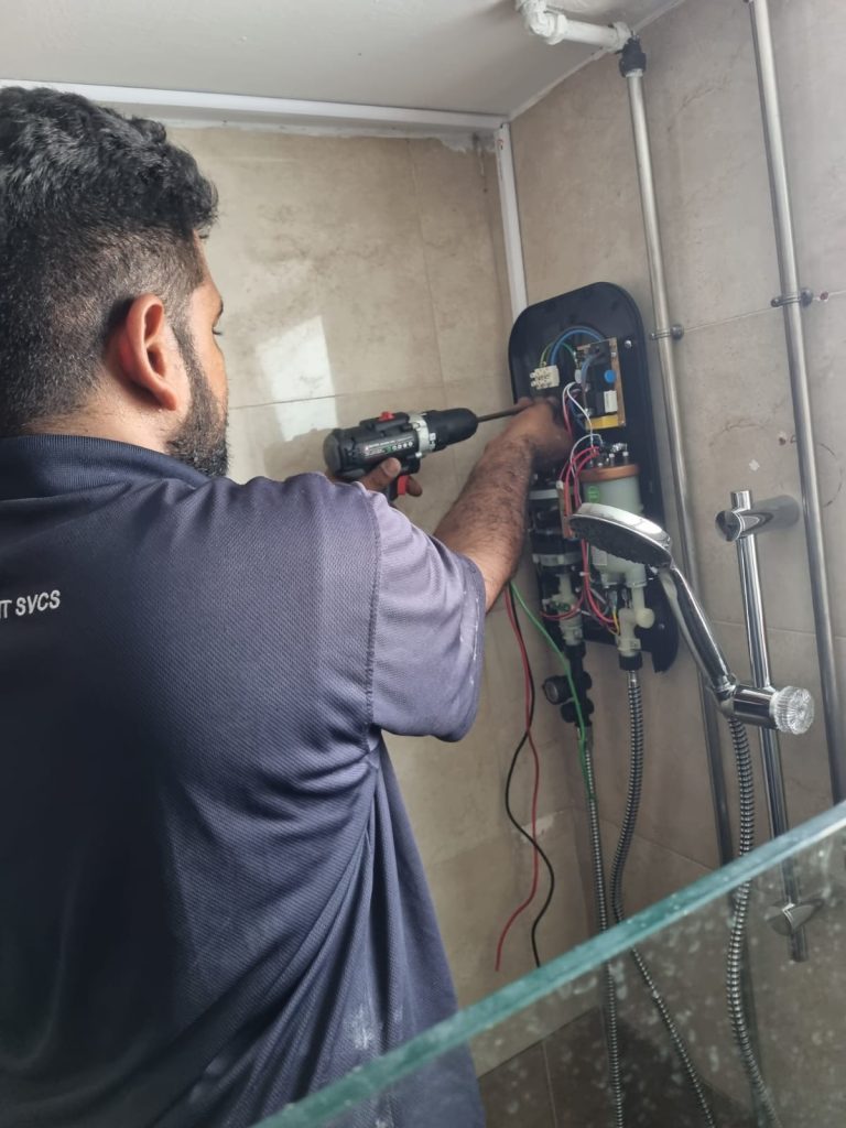 An Ezzy handyman using a drill while working on a water heater